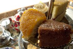 three different types of desserts on a glass plate with tea cups and saucers