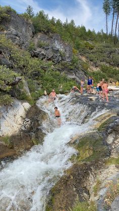 several people are swimming in a small waterfall