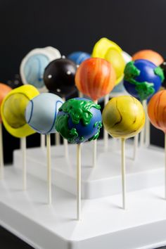 there are many cake pops with different colors on the sticks in front of each other