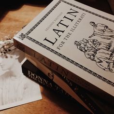 two books sitting on top of a wooden table next to a white paper with an image of a woman