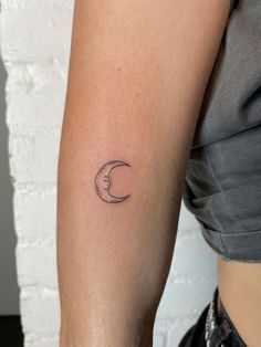 a woman's arm with a small crescent tattoo on the left side of her arm