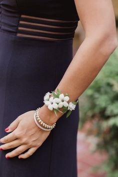 a woman wearing a bracelet with flowers on it's wrist and holding onto her hand