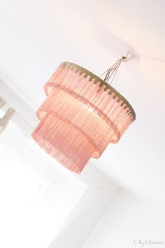 a pink chandelier hanging from the ceiling in a room with white walls and windows