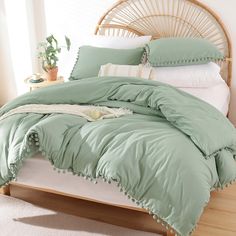 a bed with green comforter and pillows on it