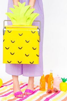 a woman holding a pineapple shaped lunch box on top of a towel next to lemons