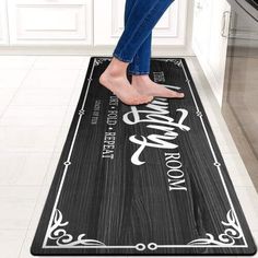 a woman standing on top of a kitchen floor next to a black and white rug