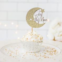 a cupcake on a plate with a cake topper that says just the moon