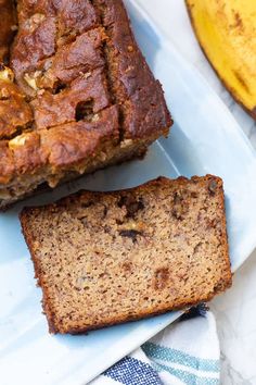 two slices of banana bread sitting on top of a blue and white plate next to bananas