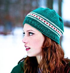 a woman with red hair wearing a green knitted hat and looking off into the distance