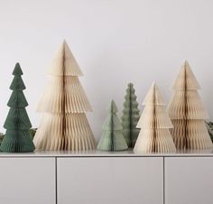 three wooden christmas trees sitting on top of a white table next to each other in front of a wall