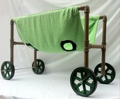 a green cloth covered stroller with wheels on a white background in front of a backdrop