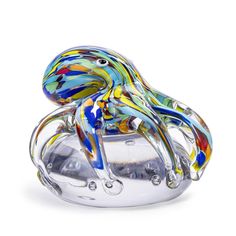 a glass figurine sitting on top of a metal container filled with colorful liquid