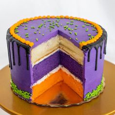 a cake with purple, orange and green frosting on a gold plated platter