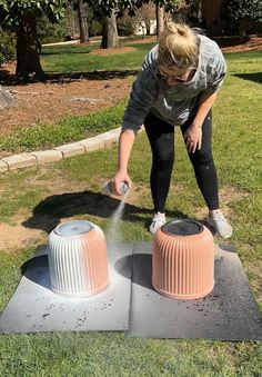 a woman is spraying water on two plastic cones