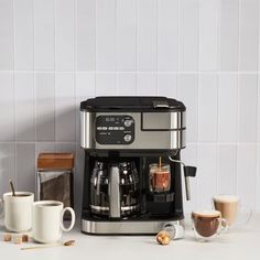 an espresso machine sitting on top of a counter next to cups and coffee mugs