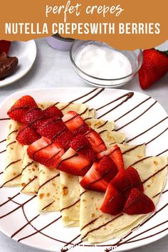 a white plate topped with crepes covered in strawberries and drizzled with chocolate