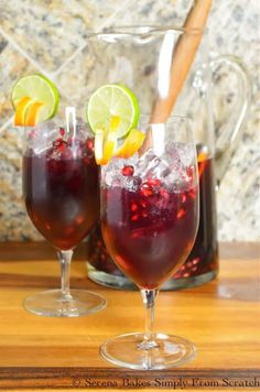 two glasses filled with red wine and garnished with limes