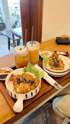 two plates with food on them sitting on a table next to a glass of orange juice