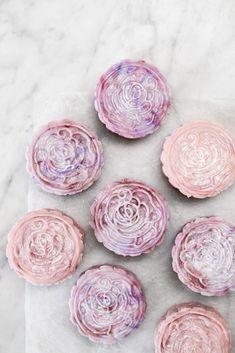 six pink and purple cupcakes sitting on top of a white countertop next to each other