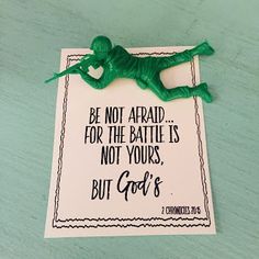 a green plastic toy laying on top of a piece of paper that says, be not afraid for the battle is not yours but god's