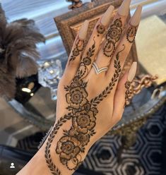 a woman's hand with henna tattoos on it and a mirror in the background