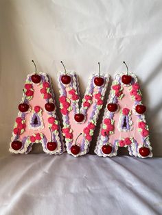 three cakes shaped like letters with cherries on them