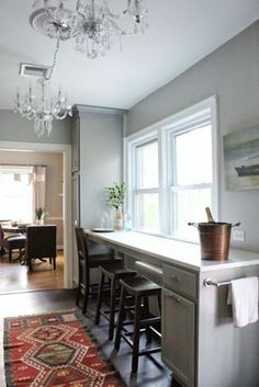 a kitchen with a chandelier hanging from the ceiling and bar stools in front of it