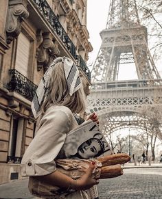 a woman is standing in front of the eiffel tower, holding a book