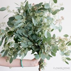 a woman holding a bouquet of flowers and greenery