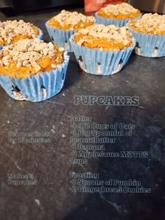 four cupcakes sitting on top of a black counter next to a sign that says pupcakes