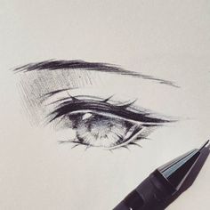 a pencil drawing of an eye with the iris drawn on paper and next to it is a black marker