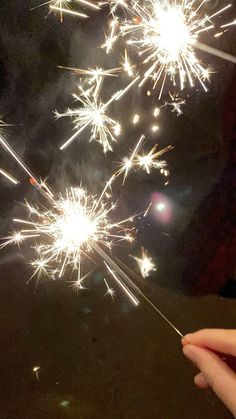 someone is holding a sparkler in their hand and it looks like fireworks are exploding