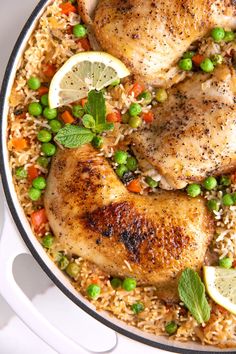 chicken and rice in a skillet with lemons, peas, and lime slices