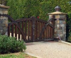 a stone and wood gate in front of some bushes