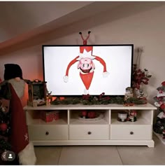 a flat screen tv sitting on top of a white dresser next to a christmas tree