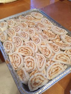 a pan filled with cinnamon rolls on top of a wooden table