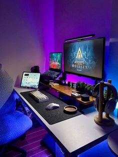 a computer desk with two monitors and a laptop on it in front of a purple wall