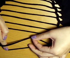 two hands holding something on top of a wooden table next to another person's hand