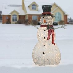 a snowman with a top hat and scarf standing in front of a house on a snowy day