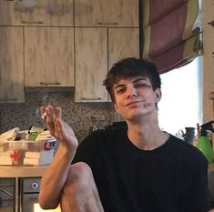 a young man sitting on the kitchen floor with his hands up in front of him