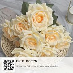 a bouquet of white roses sitting on top of a table next to a glass vase