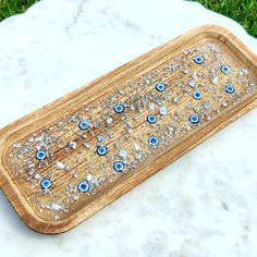 a wooden tray with blue and white glass eyes on it sitting on the ground next to some grass