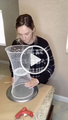 a woman is making a sculpture out of wire and plastic mesh on top of a table