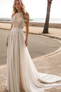 a woman in a white dress standing on the side of a road with palm trees