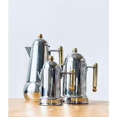 three stainless steel coffee pots and kettles on a wooden table