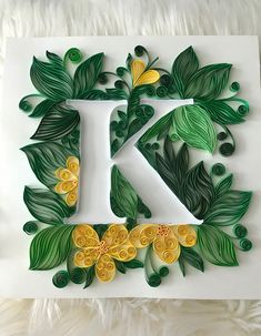 the letter k is decorated with flowers and leaves