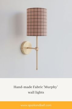 Photo of a Spark & Bell traditional wall lamp with tall round shade made of fabric with pink & marsh checkerboard pattern.