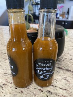 two bottles of hot sauce sitting on top of a counter