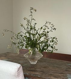 a vase filled with flowers sitting on top of a wooden table next to a white pillow