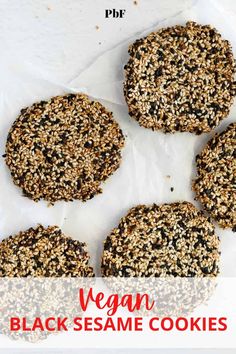 four cookies with seeds on them sitting on wax paper next to a cup of coffee